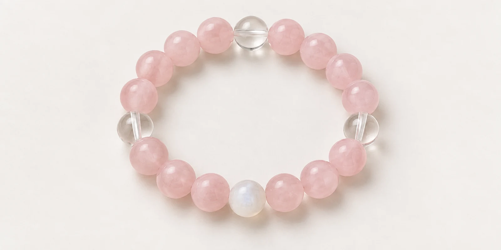 Rose quartz bracelet with clear quartz and moonstone accents on a plain background