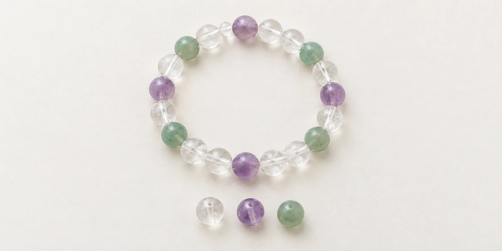 Clear quartz bracelet with amethyst and aventurine accents beside three matching loose beads