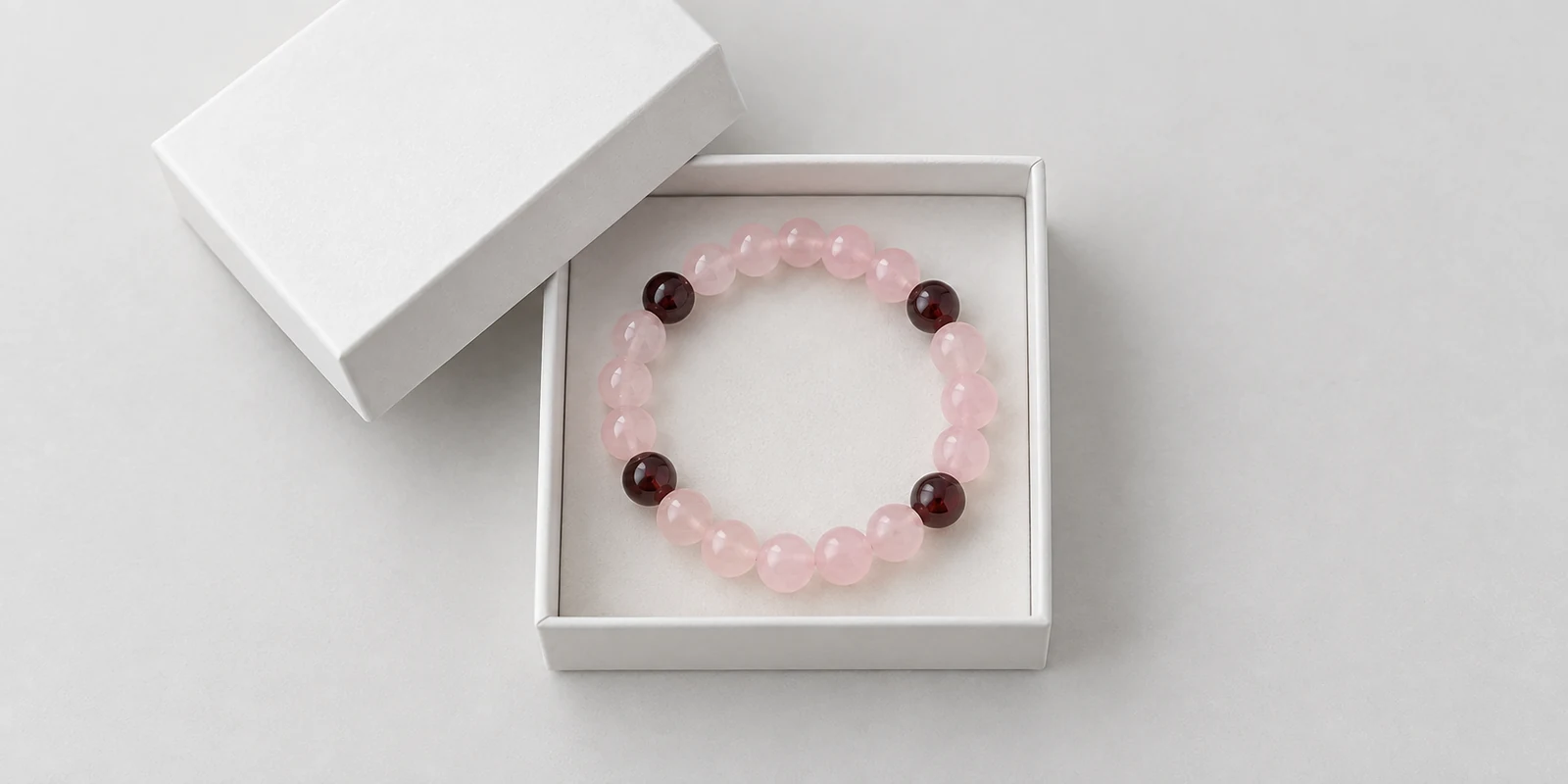 Rose quartz bracelet inside a simple white jewelry box on a plain background