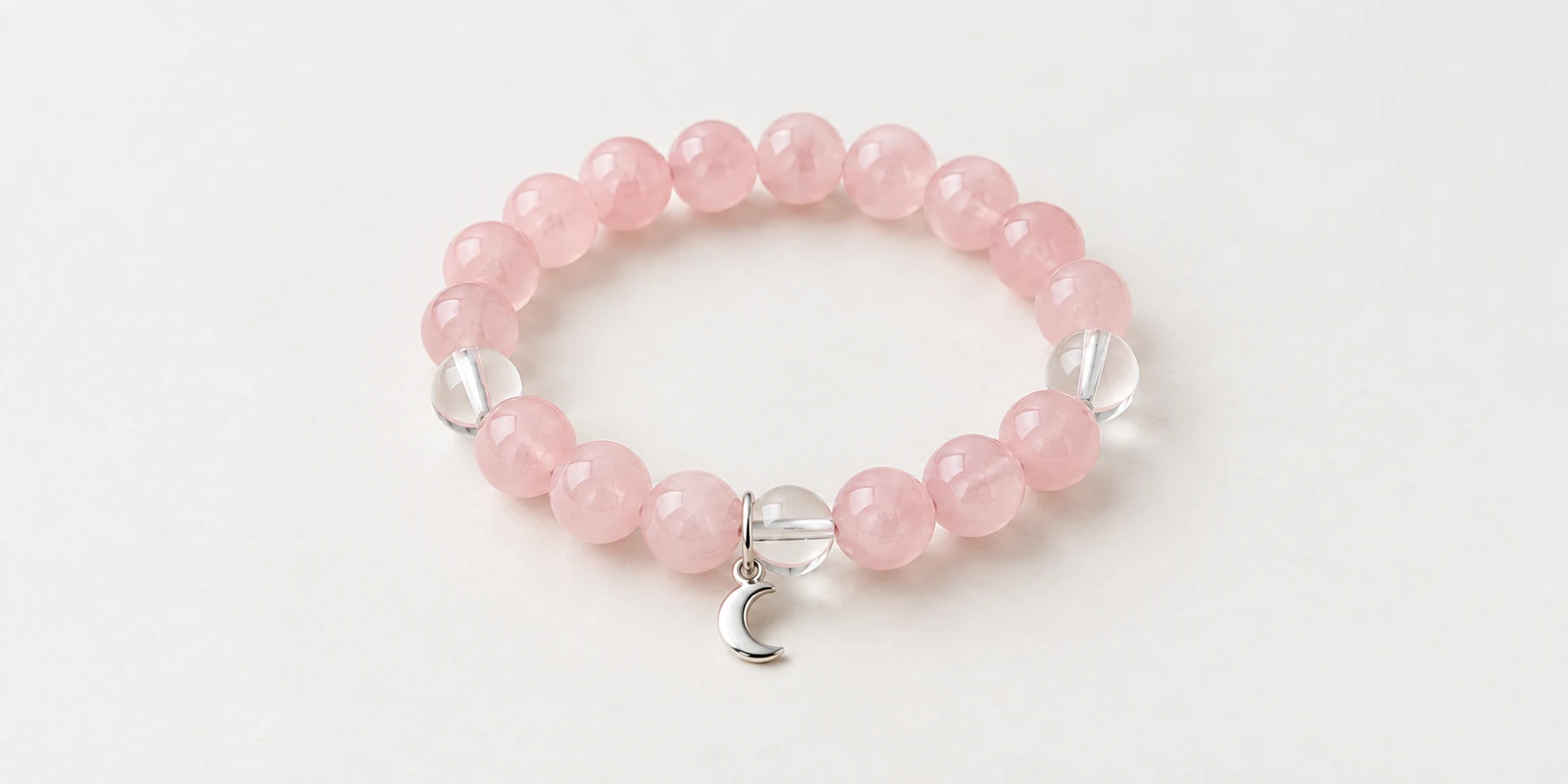 Rose quartz bracelet with clear quartz accent beads and a small silver crescent charm